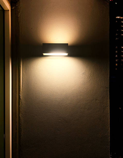 istock Glowing light fixture attached on house exterior wall at night 2222684523