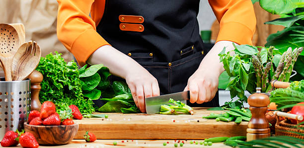 istock In a vibrant kitchen, a woman in an apron skillfully chops fresh greens surrounded by an array of colorful vegetables and herbs. 2222688620