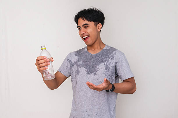 istock Young Asian man smiling and holding a water bottle with a satisfied expression, sweating after activity, isolated on white background, perfect for advertisement 2222689152