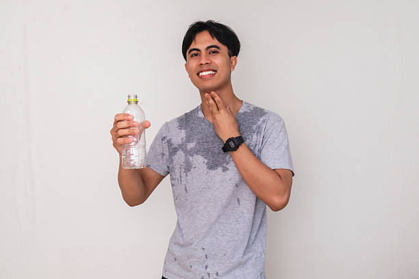 istock Young Asian man smiling and holding a water bottle with a satisfied expression, sweating after activity, isolated on white background, perfect for advertisement 2222689239