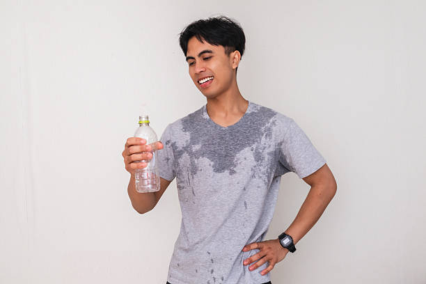 istock Young Asian man sweating and smiling while holding a water bottle and showing a satisfied gesture, isolated on white background, perfect for health and advertisement themes 2222689242