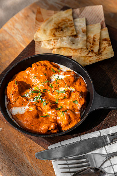 Butter Chicken dish with butter paratha on plate served at sunny outdoor Restaurant