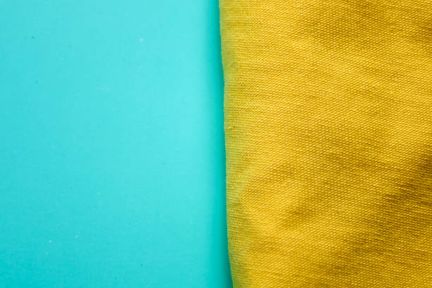 A vibrant minimalist background featuring two contrasting surfaces: a turquoise and a rich yellow fabric texture, separated by a vertical line. This creates a dynamic and attractive design, ideal for use as a background or a graphic design element.