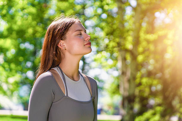istock Woman enjoying deep breaths in a serene park during sunny daylight 2222695575