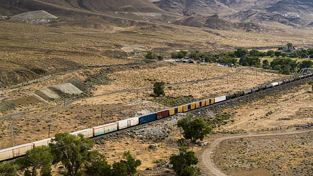 istock Cargo train crossing arid landscape. Colorful freight containers traverse Storey County, Nevada desert near small settlement. 2222705165