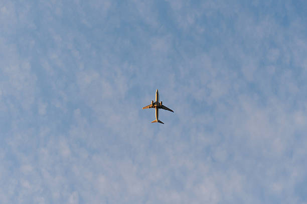 istock Airplane flying across a soft blue sky with scattered clouds. 2222706194