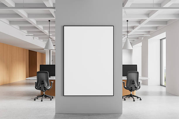 istock Blank poster frame on grey wall in modern open office with workstations, wood paneling, and pendant lights in bright daylight setting. 3D Rendering 2222711515