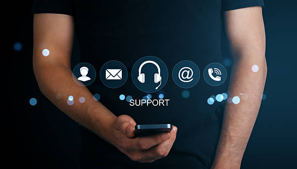 istock Man holding smartphone with glowing virtual icons representing online customer support options on dark background with blue light effects. 2222712012