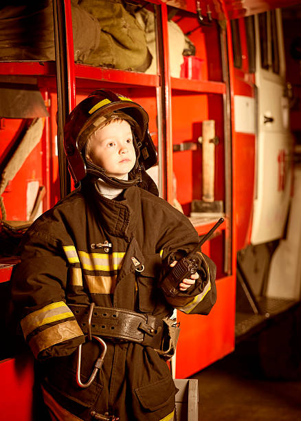 istock Serious boy in firefighter clothes at stand with firefighting equipment 2222713965