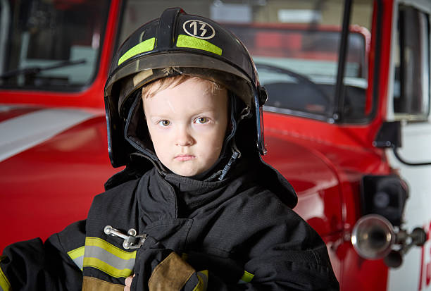 istock Cute kid firefighter in protective firefighting clothing 2222714000