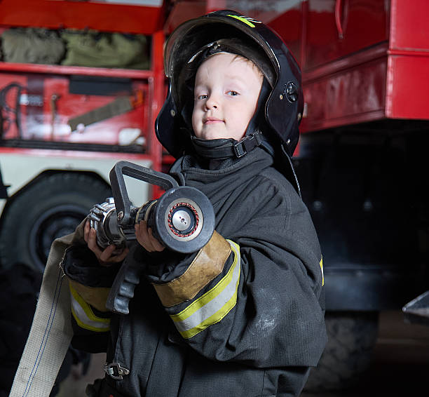 istock Brave Little Firefighter Boy With Fire Hose 2222714011