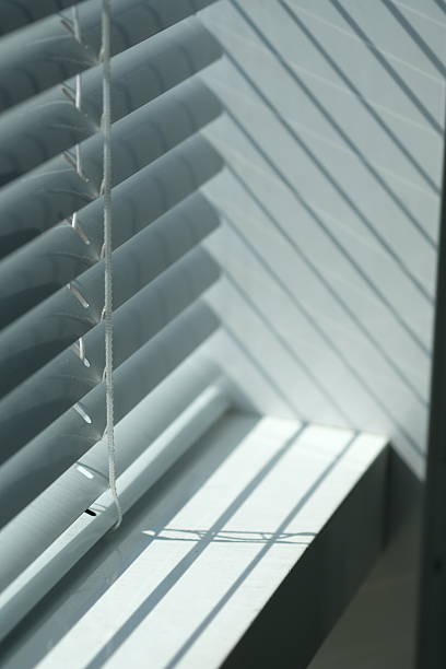 istock Light filtering through partially closed blinds creates a textured pattern in a sunlit room during morning hours 2222721719