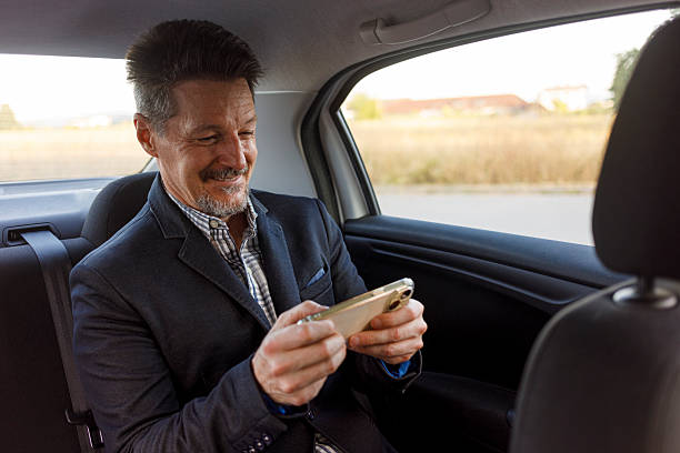 istock Smiling Man Engaged in Mobile Gaming in Car Backseat 2222722850