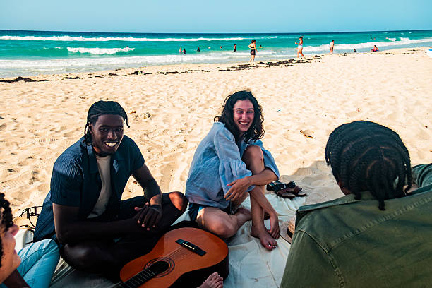 Two women on the beach sitting on the floor with a stringed musical instrument