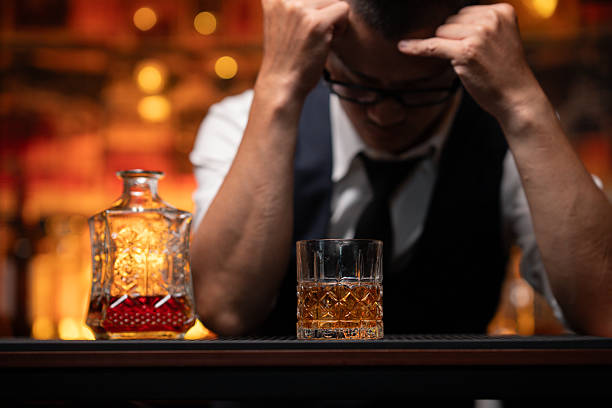 istock Handsome businessman or young man sits, drinks whiskey, looks stressed and sad. 2222726195
