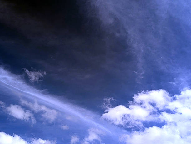 Close up of atmospheric blue black sky with whispy white clouds