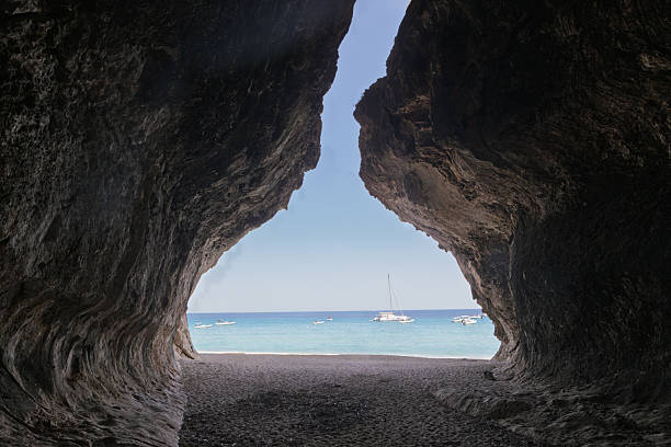 istock Sunny beach and boats seen through shadowy cave opening 2222728297