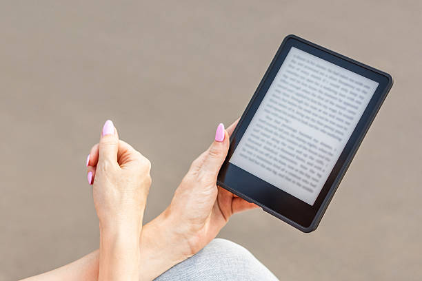 istock woman reading e-book sitting on bench in city park. 2222728929
