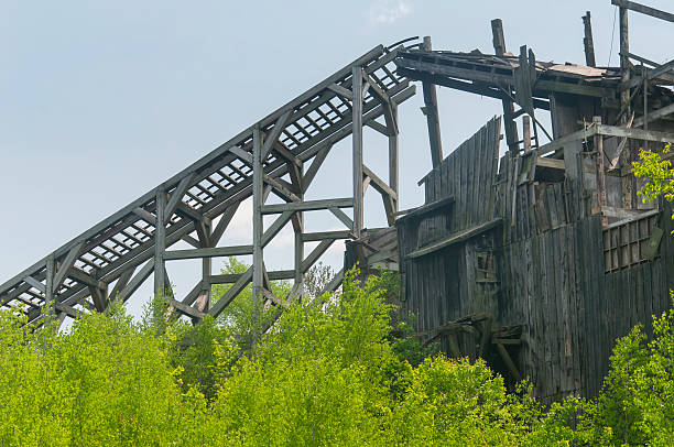 A dilapidated coal processing building surrounded by overgrown plants in eckley miners village on a spring day in weatherly pennsylvania.