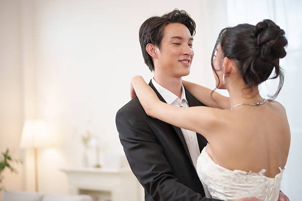 istock Asian bride and groom share a gentle moment, smiling while looking into each other. Romantic moment full of love and connection, couple shares a sweet wedding anniversary. 2222744582
