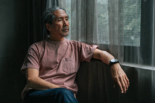 istock Pensive Mature Japanese Man Sitting by Rainy Window 2222745186