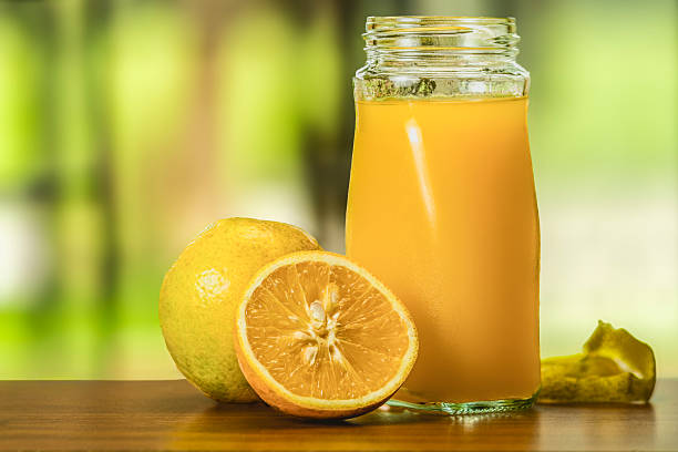 istock Fresh orange juice in a glass, with a blurry green background. 2222748339