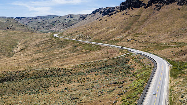 istock Mountain pass road curves through rugged terrain. Single vehicle travels empty highway in Owyhee County, Idaho. 2222751573