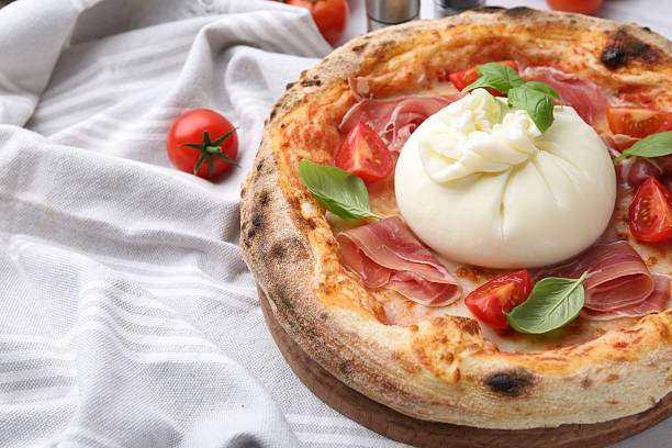 istock Delicious pizza with burrata cheese, basil, tomatoes and ham on table, closeup 2222755954