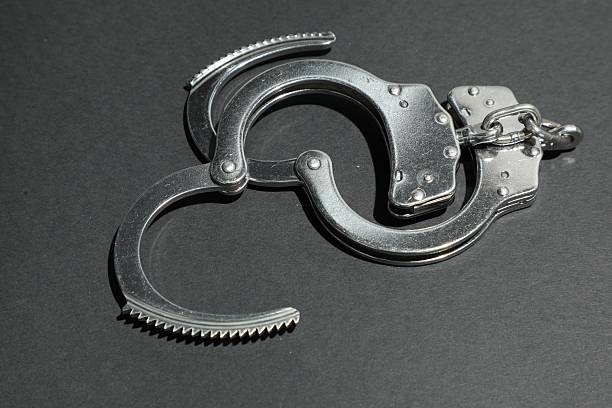 Classic chain handcuffs on black background, closeup