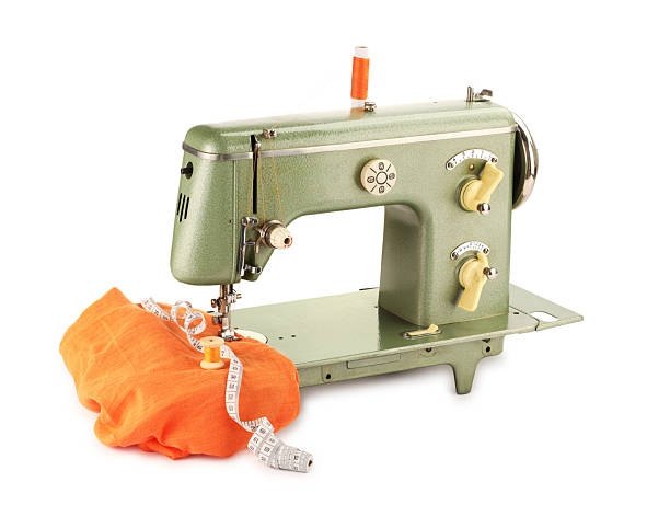 Sewing machine with orange fabric, measuring tape and spools of threads isolated on white