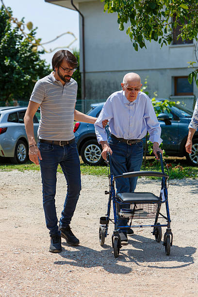 Caring young man supports elderly man for walking\nItaly, 2025