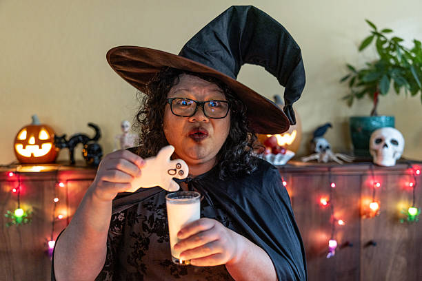 Portrait of a Asian American woman dressed as a witch with a tray of delicious treats.