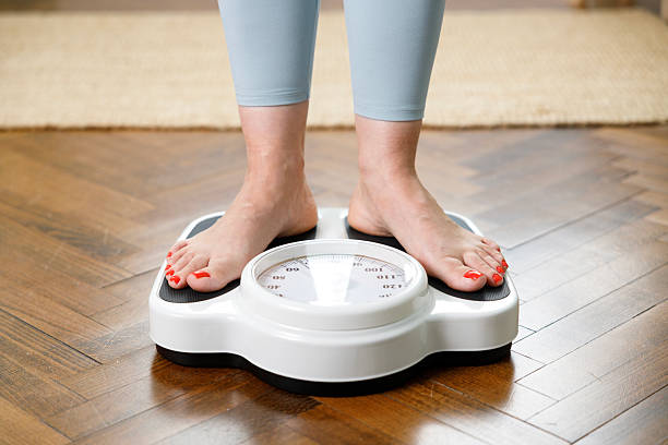 istock Woman checking weight on scale at home 2222771593