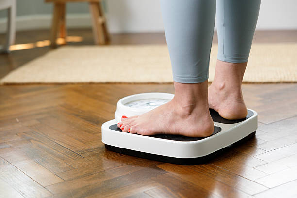 istock Woman checking weight on scale at home 2222771661
