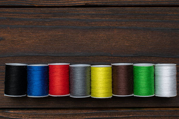 istock Colorful Thread Spools on Dark Wooden Background for Craft and Sewing Projects 2222771702