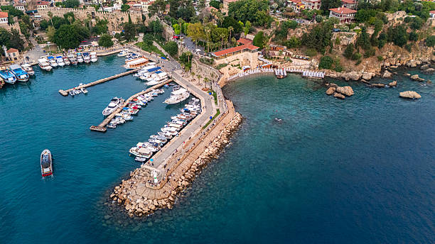 Aerial view of Antalya’s historic harbor and Kaleiçi old town. Ancient stone walls, Ottoman-era houses, and modern yachts coexist in this coastal heritage site on Turkey’s Mediterranean shore