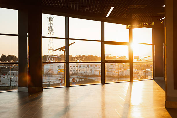 A man walks alone through a brightly lit airport terminal, holding a travel bag as the sun sets behind him. His silhouette and long shadow reflect on the polished floor, creating a cinematic, introspective scene that captures the emotional tone of travel and departure.