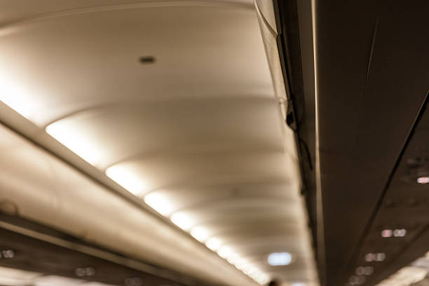 Interior view of an airplane cabin filled with passengers as a flight attendant walks down the aisle. The image captures the everyday inflight experience from a passenger’s perspective, highlighting the dynamic and human aspect of commercial air travel.
