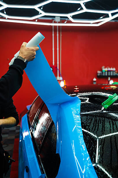 istock Wet PPF Wrapping on Car Panel in detailing center. Protective film layering during PPF wrap detailing to protect the car surface from scratches and UV. 2222787297