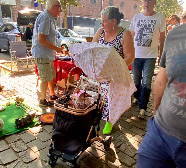 Turnhot, Belgium ~ June 29,  2025.  Couple walking with there Pussycat in  a baby carriage on the vintage Market.