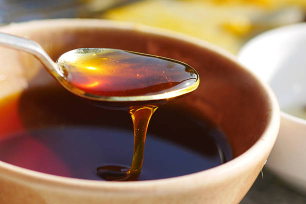 istock Honey dripping from a spoon in a rustic bowl outdoors 2222790555
