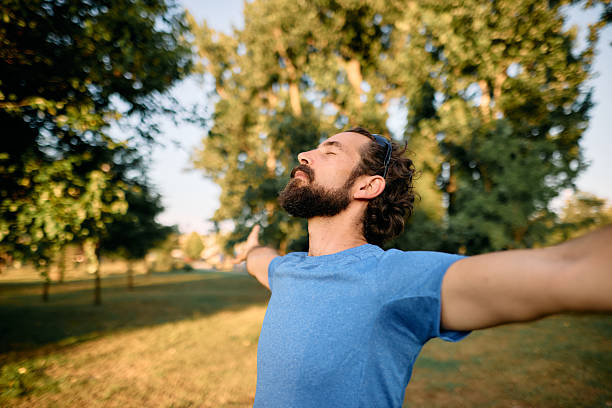 istock Man breathing fresh air in a park with open arms 2222794451