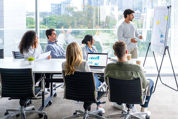 istock Business people watching a presentation on the whiteboard. A man is writing on the whiteboard with charts and graphs. 2222794681