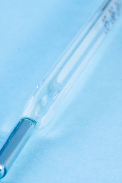 High-quality macro photograph of a mercury thermometer on a uniform light blue background. Perfect for highlighting themes of scientific and medical themes