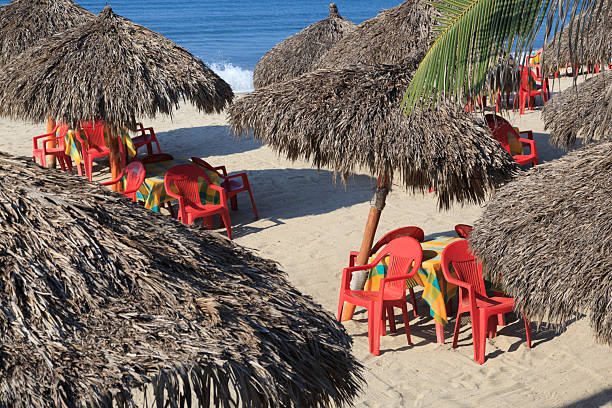 istock Mexico, Nayarit State, Bucerias. Tables, chairs, and thatched umbrellas on the beach. 2222804480