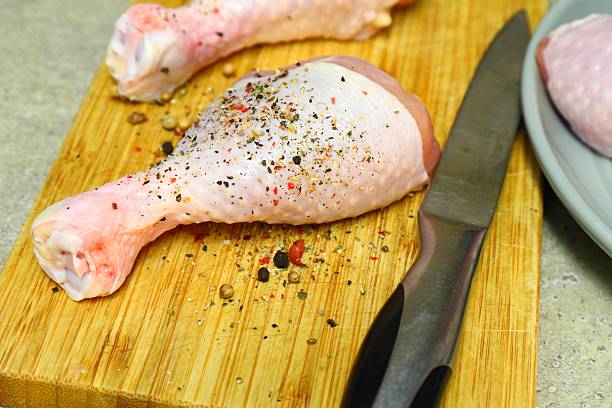istock Raw chicken legs with pepper and spices on a board and plate ready for 2222809856