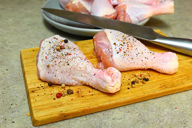 istock Raw chicken legs with pepper and spices on a board and plate ready for 2222809860