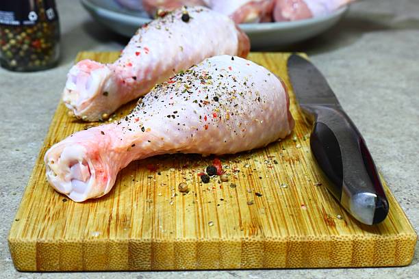 istock Raw chicken legs with pepper and spices on a board and plate ready for 2222809864
