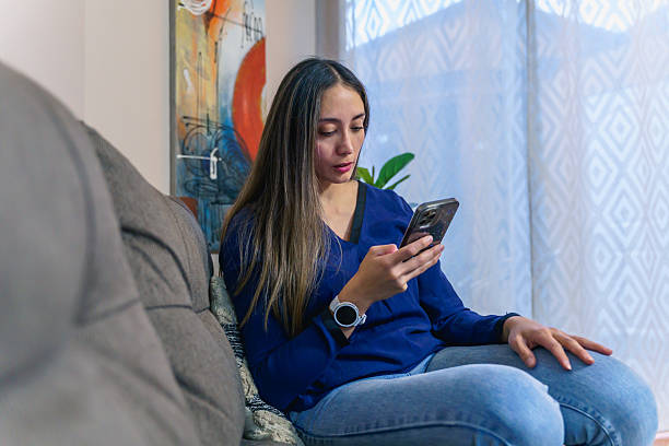 istock Young woman using smartphone while relaxing on sofa at home 2222810906