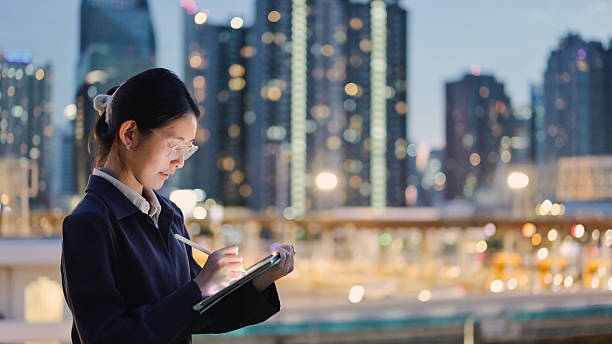istock female entrepreneur gen z woman using smart device working on digital tablet at night with illuminated city skyline in downtown city for fintech and digital business 2222819420